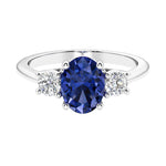 Three stone oval cut blue sapphire and diamond ring in classic design.
