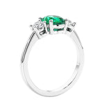 Oval cut three stone colombian emerald and diamond engagement ring with romantic charm.
