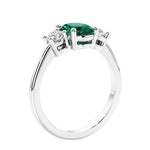 Oval cut three stone emerald and diamond engagement ring with romantic charm.