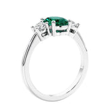 Oval cut three stone emerald and diamond engagement ring with romantic charm.