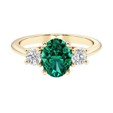 Oval 3 stone engagement ring with emerald and brilliant diamond side stones.