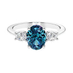 Three stone oval cut diamond ring in classic design featuring alexandrite center.