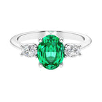 Three stone oval cut diamond ring in classic design featuring colombian emerald center.