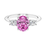 Three stone oval cut diamond ring in classic design featuring pink sapphire center.