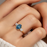 Hand adorned with oval 3 stone diamond ring in yellow gold featuring color changing real alexandrite.