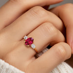 Hand adorned with oval 3 stone diamond ring in yellow gold.