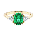 Oval cut three stone diamond engagement ring with romantic charm with green gemstone center 14k yellow gold