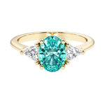 Oval cut three stone diamond engagement ring with romantic charm with green gemstone center 14k yellow gold