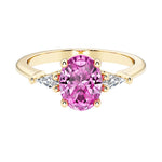 Oval cut three stone pink sapphire engagement ring with diamonds set yellow gold.