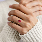 Hand adorned with oval 3 stone ruby diamond ring in yellow gold.