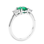 Engagement ring with oval shaped green gemstone and diamonds in a 3 stone design.
