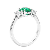 Engagement ring with oval shaped green gemstone and diamonds in a 3 stone design.