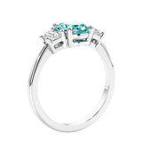 Engagement ring with oval shaped green gemstone and diamonds in a 3 stone design.