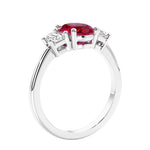 Engagement ring with oval shaped red gemstone and diamonds in a 3 stone design.