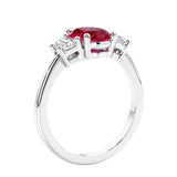 Engagement ring with oval shaped red gemstone and diamonds in a 3 stone design.