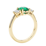 3 stone wedding ring with oval center green gemstone and diamond side stones.