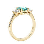 3 stone wedding ring with oval center green gemstone and diamond side stones.