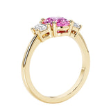 3 stone wedding ring with oval center pink gemstone and diamond side stones.