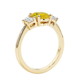 3 stone wedding ring with oval center yellow gemstone and diamond side stones.