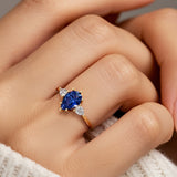 Woman wearing pear shaped three stone engagement ring with romantic flair.