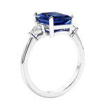 3 stone emerald cut diamond ring in modern gold setting with gemstone center.