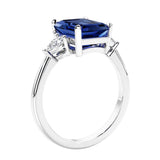 3 stone emerald cut diamond ring in modern gold setting with gemstone center.
