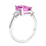 3 stone emerald cut diamond ring in modern gold setting with gemstone center.