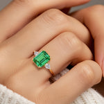 Woman wearing emerald cut three stone engagement ring with bold lines.
