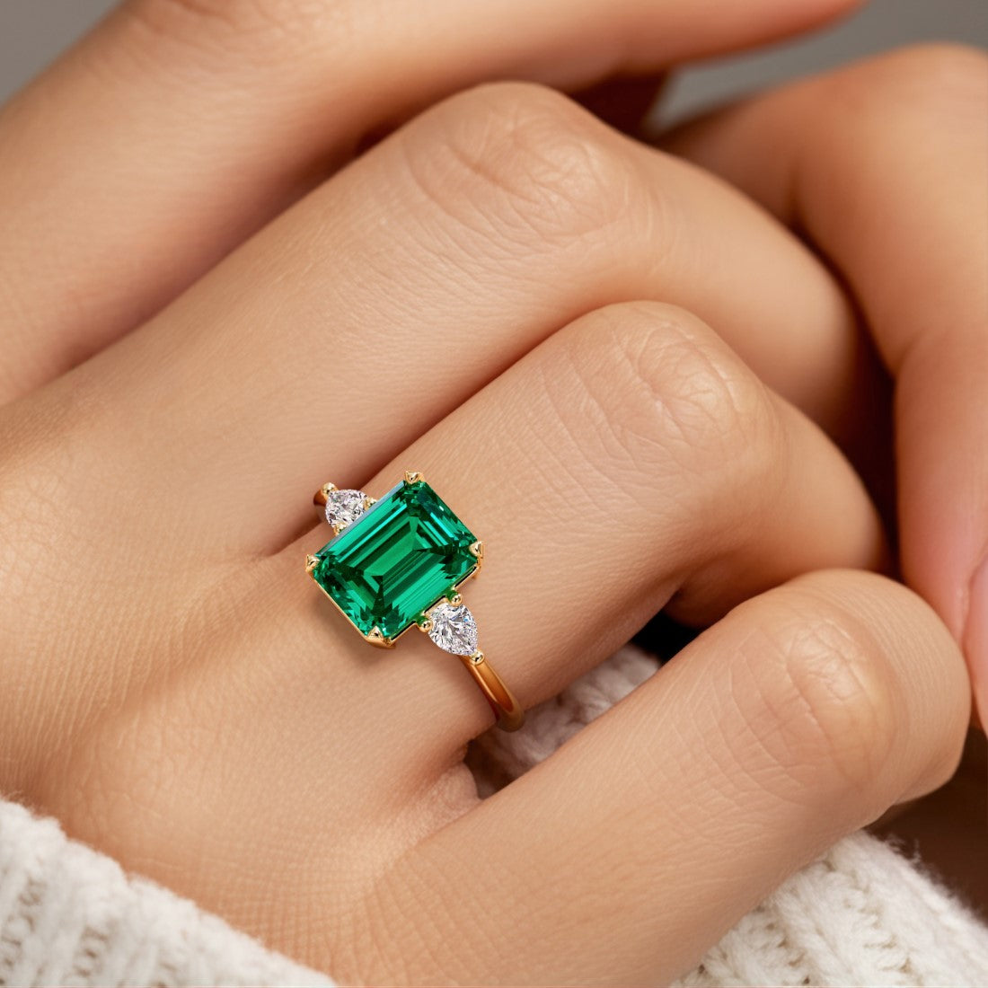 Woman wearing emerald cut three stone engagement ring with bold lines.