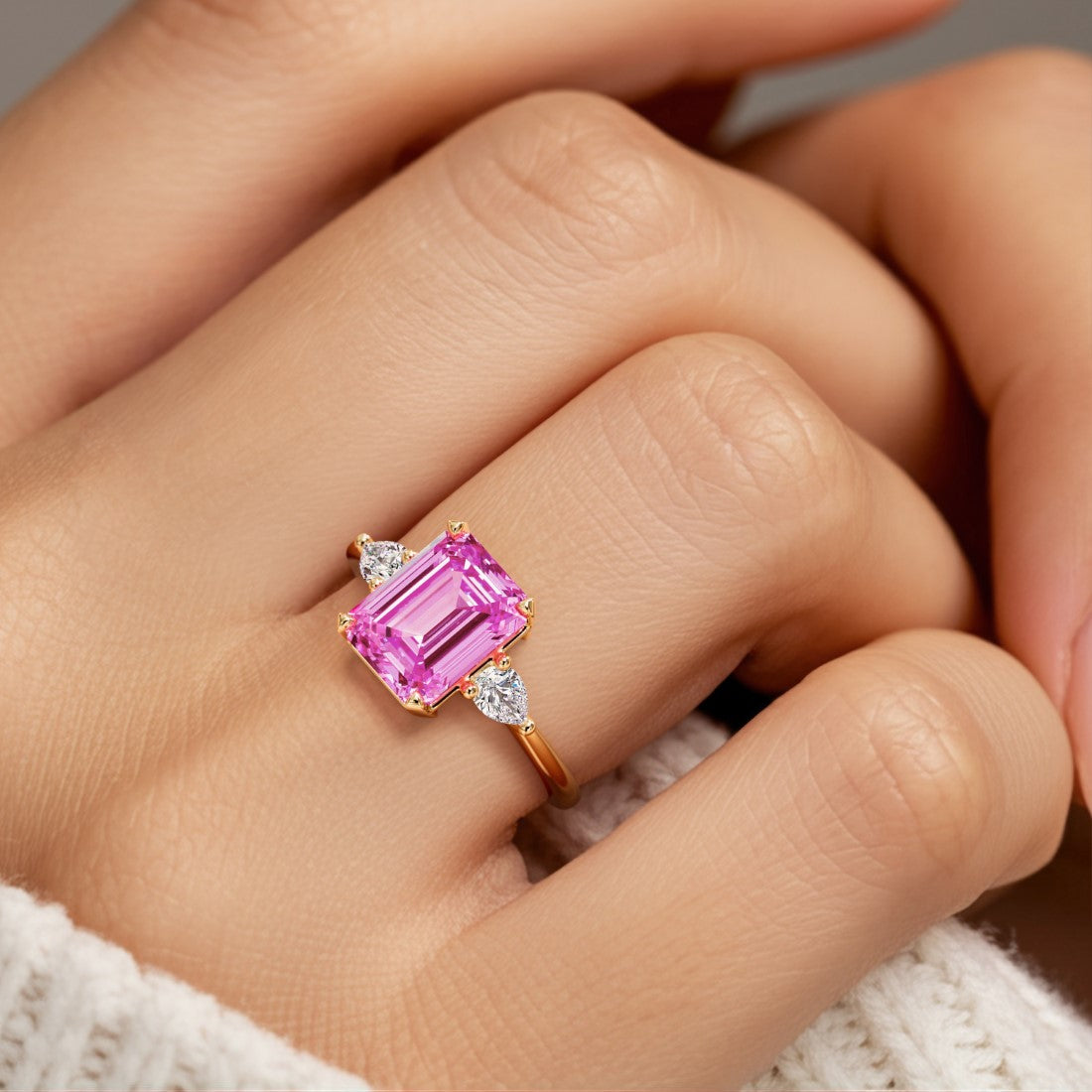 Woman wearing emerald cut three stone engagement ring with bold lines.