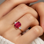 Woman wearing emerald cut three stone engagement ring with bold lines.