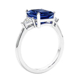 3 stone emerald cut diamond ring in modern gold setting with blue gemstone center.