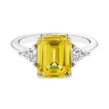 Three stone emerald cut engagement ring for timeless elegance featuring yellow gemstone and diamonds.