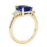 Emerald cut 3 diamond ring representing past, present, and future featuring blue gemstone center.