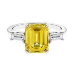 Three stone emerald cut engagement ring for timeless elegance featuring yellow gemstone and diamonds.
