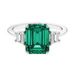 Three stone emerald cut engagement ring for timeless elegance featuring green gemstone and diamonds.