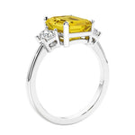 3 stone emerald cut diamond ring in modern gold setting with yellow gemstone center.