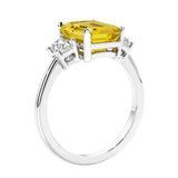 3 stone emerald cut diamond ring in modern gold setting with yellow gemstone center.