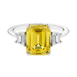 Three stone emerald cut engagement ring for timeless elegance featuring yellow gemstone and diamonds.