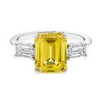Three stone emerald cut engagement ring for timeless elegance featuring yellow gemstone and diamonds.