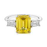 Three stone emerald cut engagement ring for timeless elegance featuring yellow gemstone and diamonds.