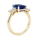 Emerald cut 3 diamond ring representing past, present, and future featuring blue gemstone center.