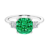 Cushion shaped engagement ring with brilliant diamonds and green gemstone.