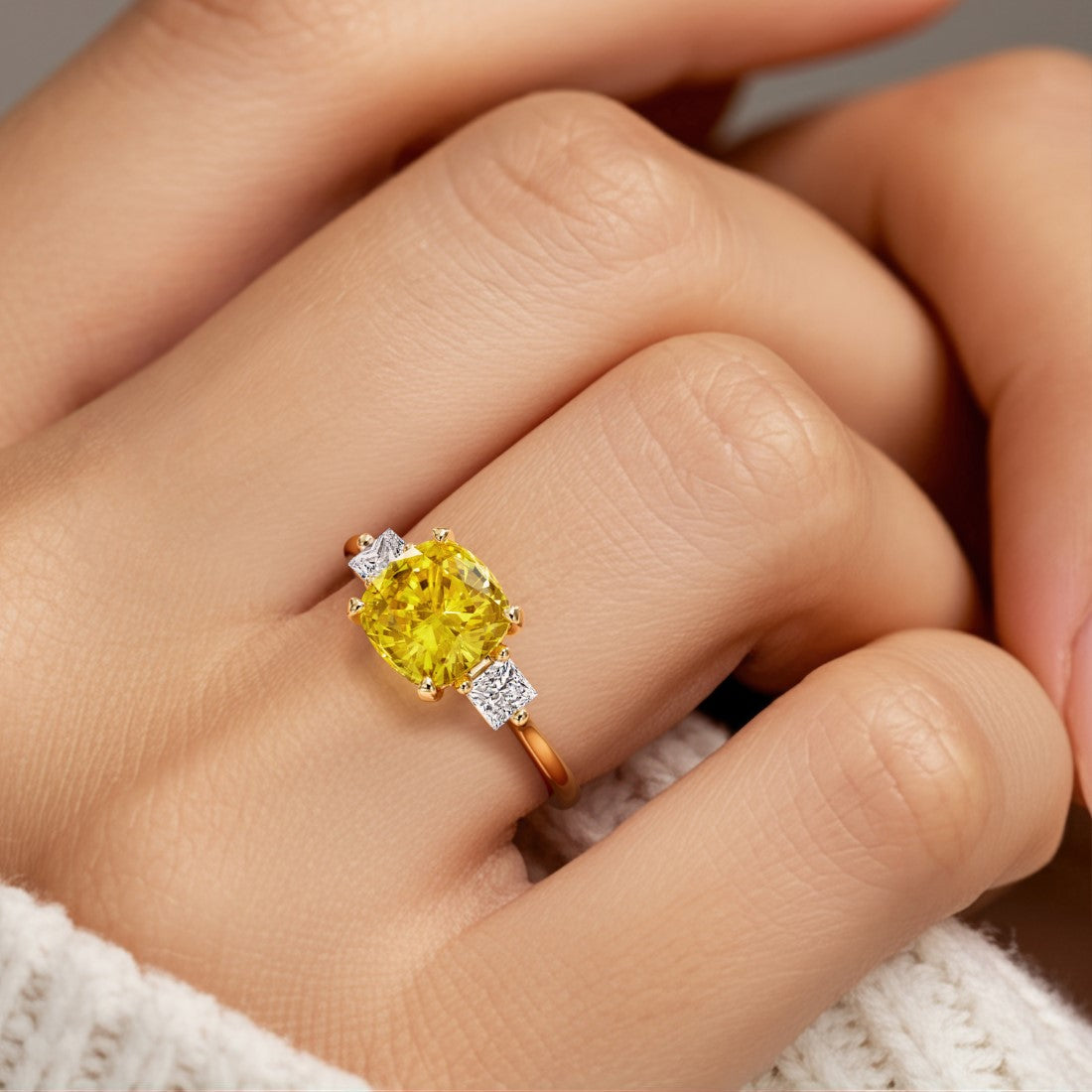 Woman wearing a cushion cut 3 stone ring with romantic styling featuring yellow gemstone and diamonds.
