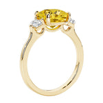 Three stone cushion diamond ring in yellow gold setting with yellow gemstone and diamonds.