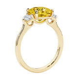 Three stone cushion diamond ring in yellow gold setting with yellow gemstone and diamonds.