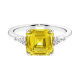 Asscher gemstone diamond ring with step-cut sparkle in a three stone setting featuring yellow sapphire center.