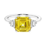 Asscher gemstone diamond ring with step-cut sparkle in a three stone setting featuring yellow sapphire center.