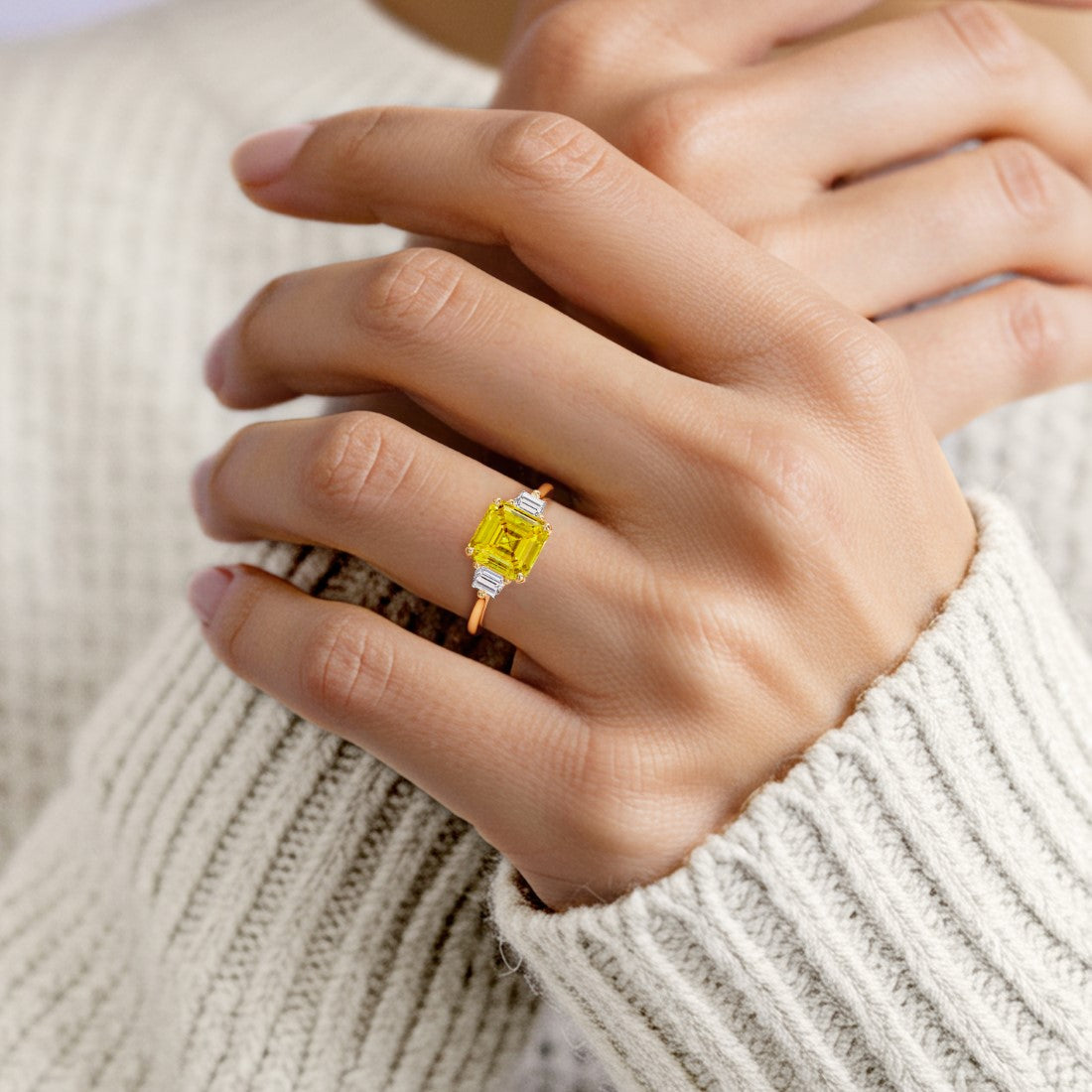 Woman wearing a 3 stone Asscher engagement ring with vintage flair featuring a yellow sapphire center.
