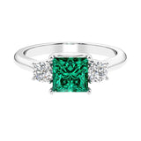 3 stone princess diamond ring in sleek white gold with emerald gemstone.